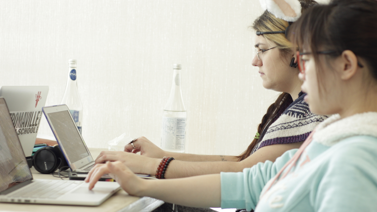 Milin and Gersande sitting at computers testing the game.