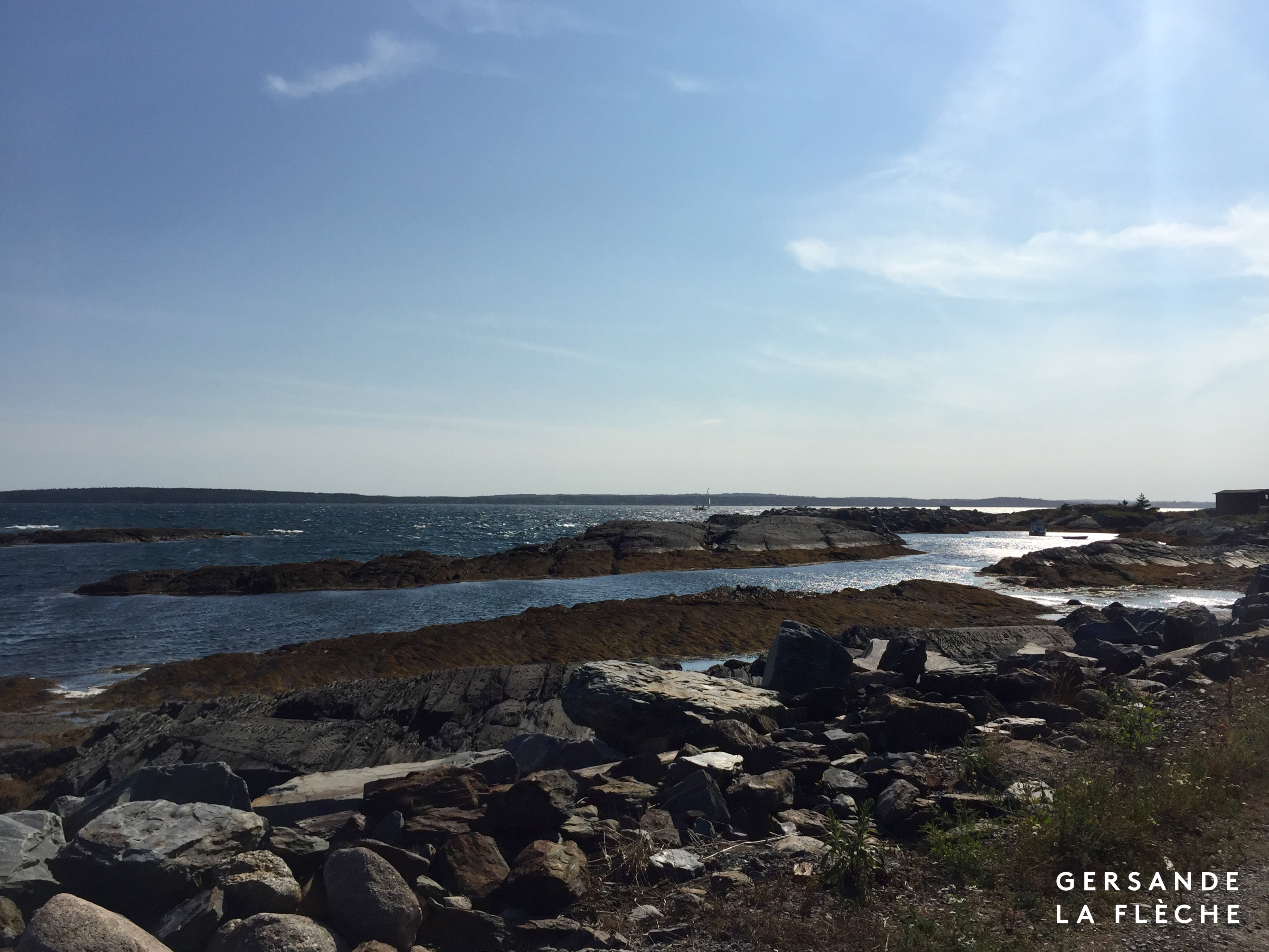 A picture of a blue sky over blue rocks lowering into the ocean.