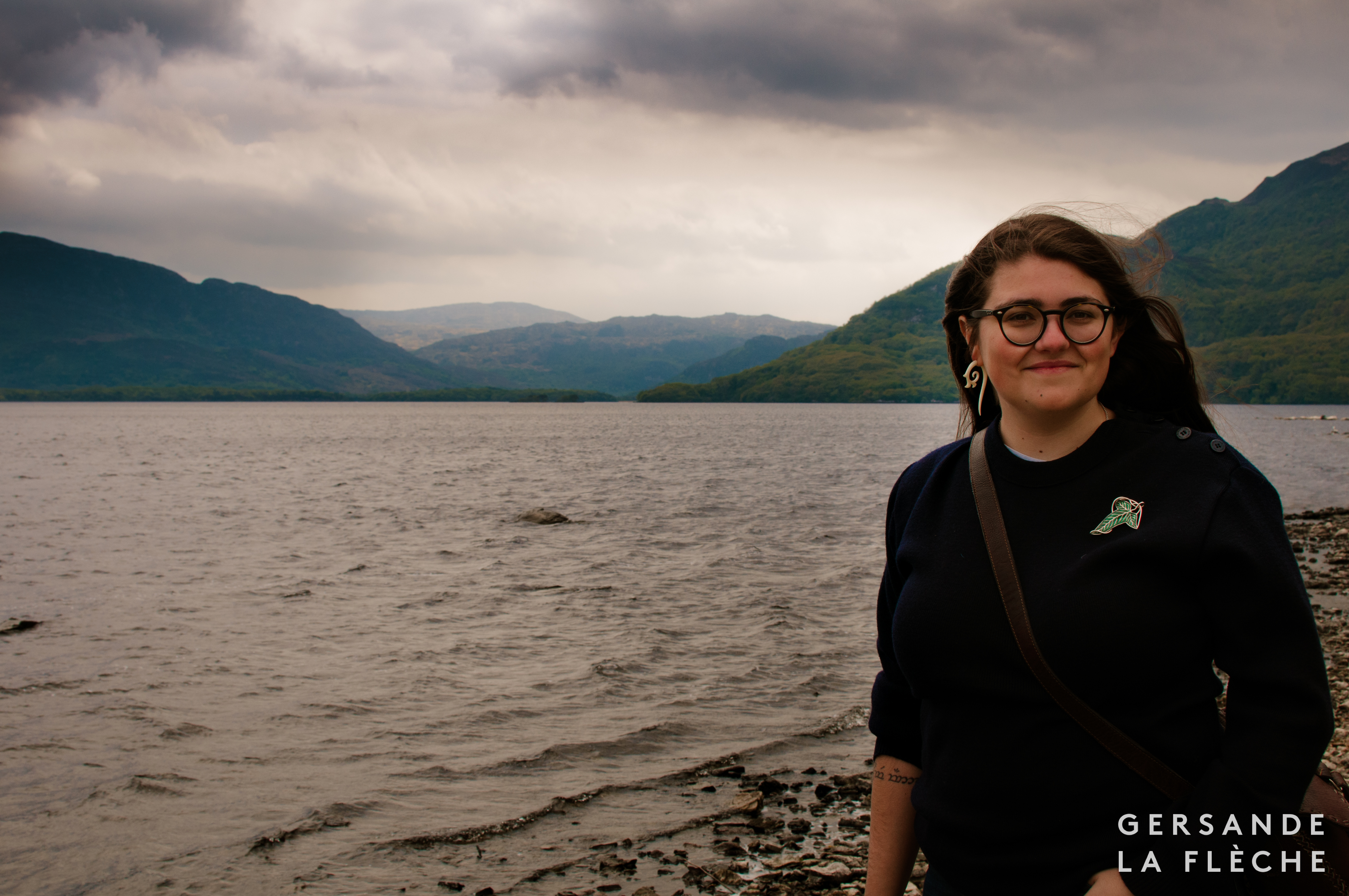 A photograph of the author in front of storm clouds, and the silvery lake of Lough Leane, the Killarney mountains in the background.