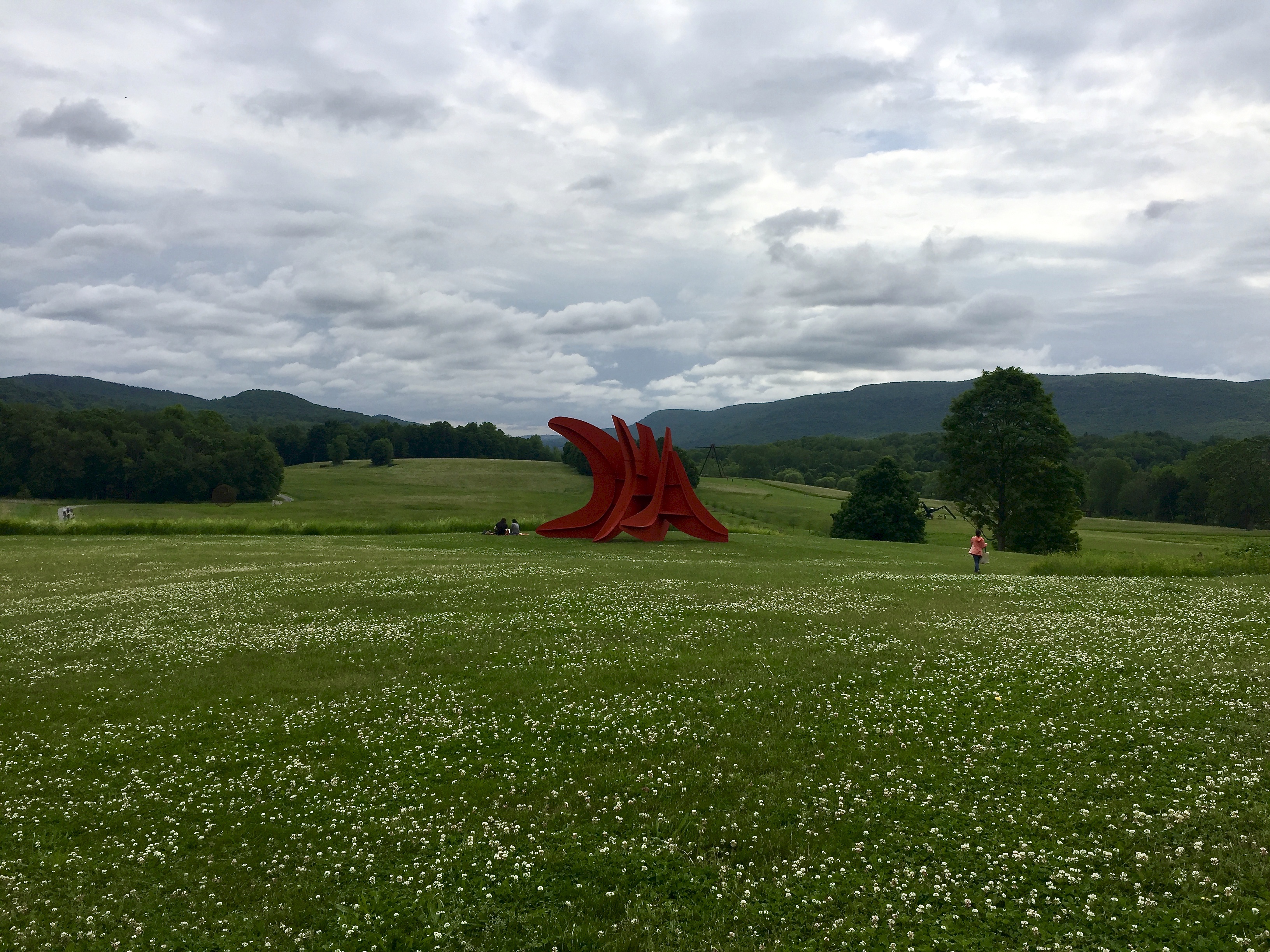 A photo of Five Swords, 1976, by Alexander Calder sitting in a green field.