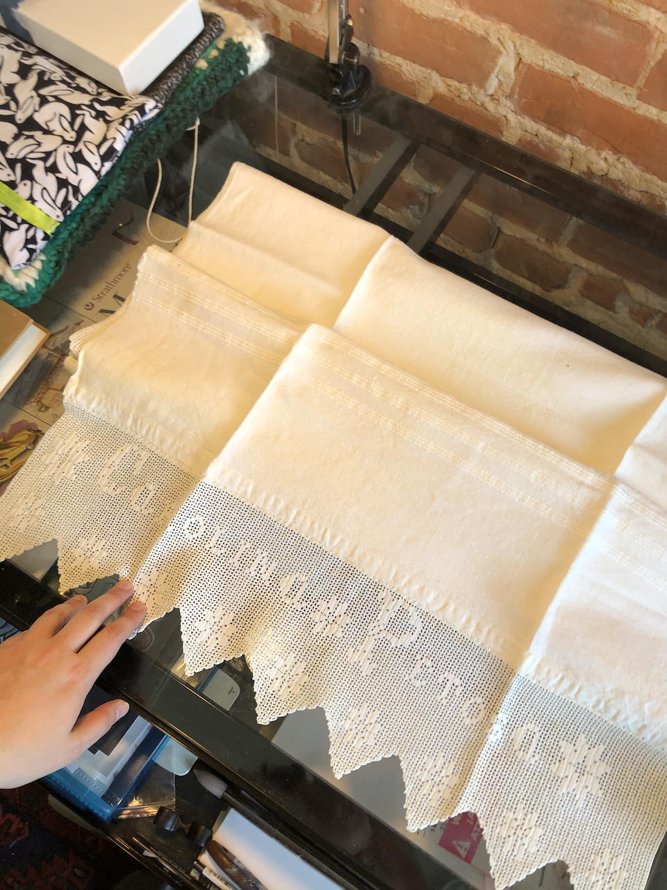 A photo of some folded linen, with the end visible. Amongst the embroided star-flowers is the name "Carolina Petosa". 