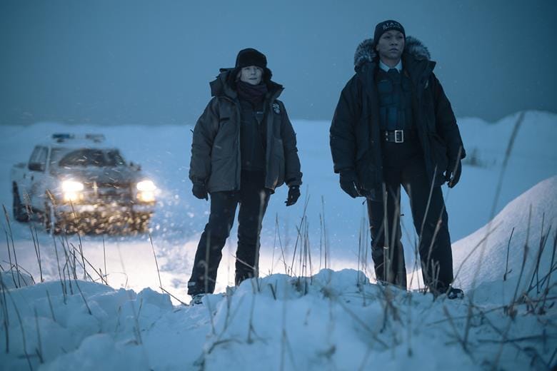 A screenshot of a still from the True Detective season 4, where Foster and Reis' characters are standing in the snow and looking over a snowbank.